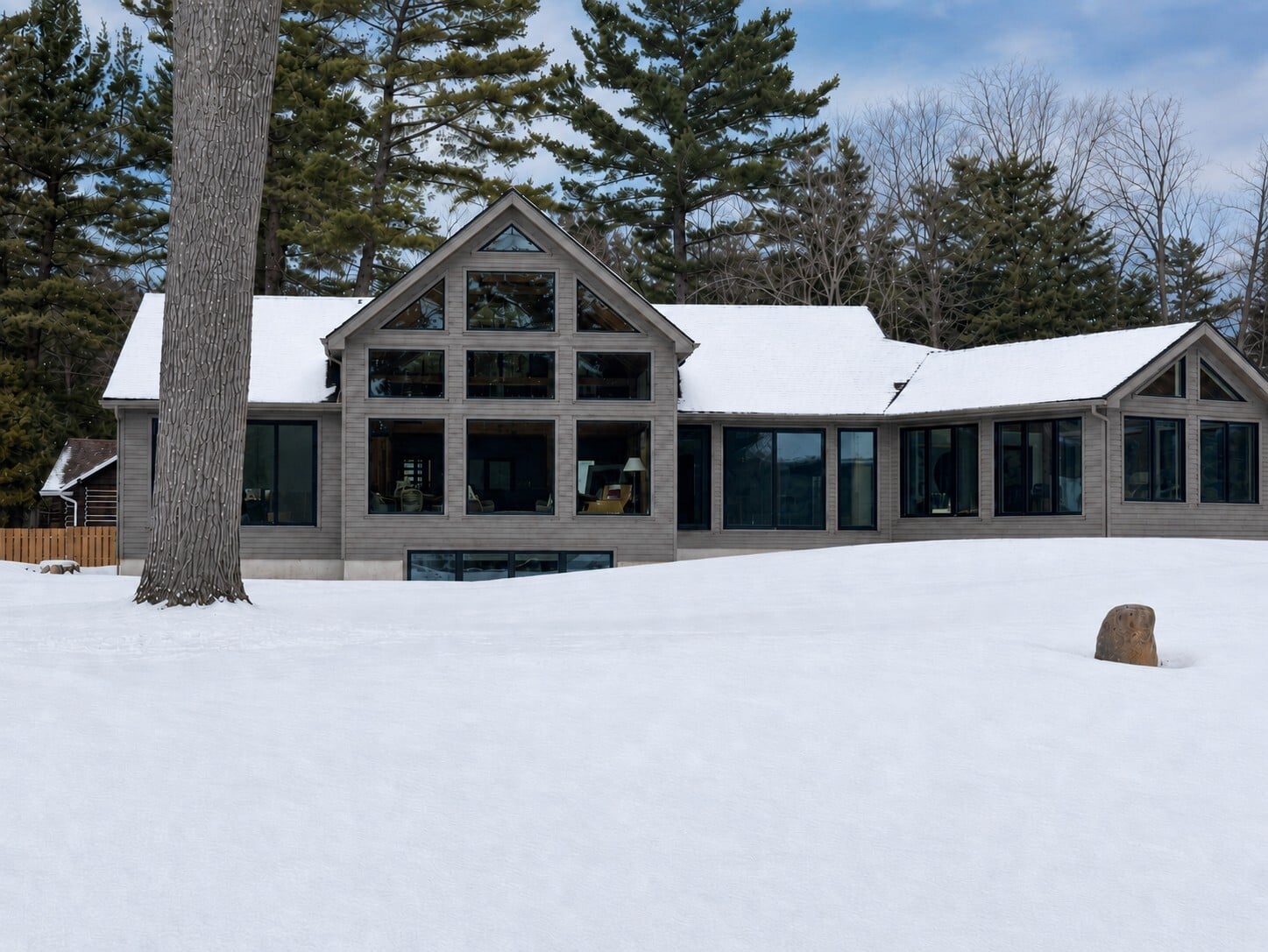 Customized Normerica Rocklyn timber frame home on Georgian Bay in winter, featuring a two-storey window wall and four-season sunroom addition